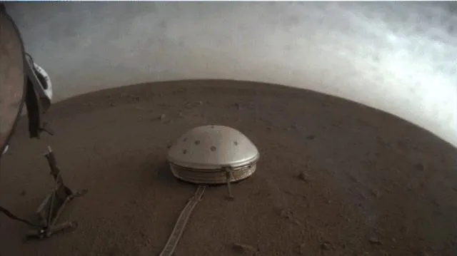 Graue Wolken ziehen über den Marshimmel in dieser Aufnahme des NASA-Landers InSight. Die Raumsonde fotografierte die treibenden Wolken während eines Sonnenuntergangs auf dem Roten Planeten am 25. April mit ihrer Instrument Context Camera, die unterhalb der Plattform montiert ist. Im Vordergrund, auf dem Boden sitzend, befindet sich das Seismic Experiment for Interior Structure (SEIS)-Instrument, das nach seismischer Aktivität oder "Marsbeben" sucht.