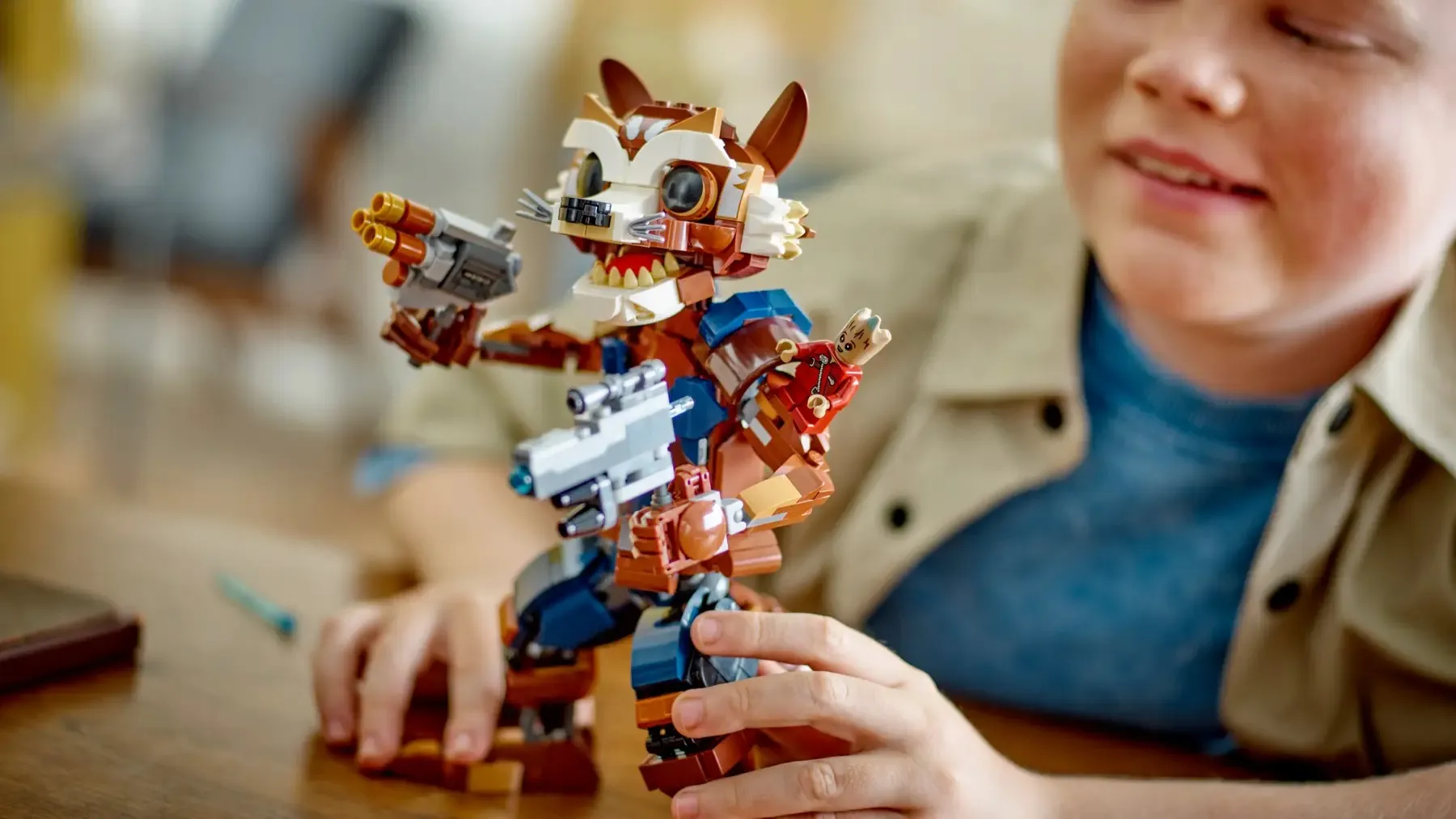 Eine fertige Lego Marvel Rocket und Baby Groot, mit denen ein Junge spielt.